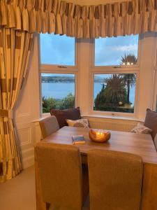 a dining room with a table and two windows at Bayside - Breathtaking views of the Clyde in Rothesay