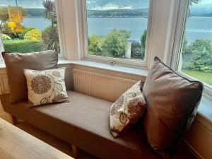 a bench with pillows sitting in front of a window at Bayside - Breathtaking views of the Clyde in Rothesay
