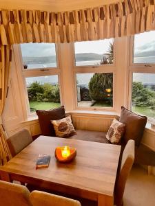 a living room with a table and two windows at Bayside - Breathtaking views of the Clyde in Rothesay