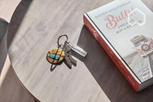 a pair of keys on a table next to a book at TomsFlat VW Bulli Apartment Wolfsburg in Wolfsburg