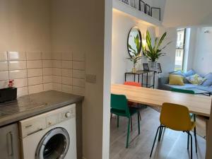 een keuken en een woonkamer met een wasmachine en een tafel bij Modern & Spacious 2BD Apartment in Limehouse in Londen