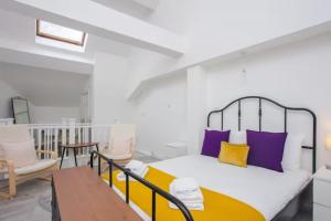 1 dormitorio con 1 cama con almohadas moradas y amarillas en Modern & Spacious 2BD Apartment in Limehouse en Londres