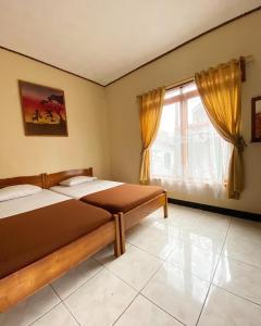 1 dormitorio con 2 camas y ventana en Rinjani Homestay, en Pangandaran