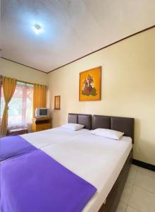 a bedroom with two large beds with purple sheets at Rinjani Homestay in Pangandaran