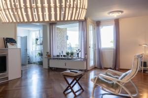 a living room with a chair and a desk and windows at Elegante Ferienwohnung am See in Düsseldorf