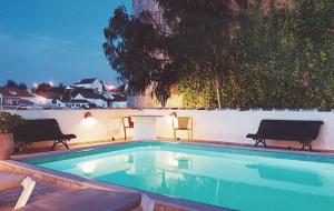 a swimming pool with two benches next to a wall at Casa do Rio / Tavira Inn - Adults Only in Tavira