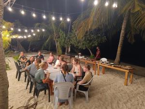 a group of people sitting at tables on the beach at night at The Sunset Villa in Dhiffushi