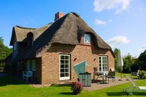 uma casa com telhado de palha, mesa e cadeiras em Pesel em Borgsum