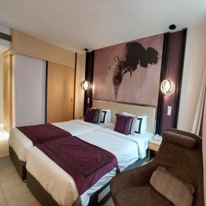 a hotel room with two beds and a chair at BEYZAA HOTEL AND SUITES in Kolkata