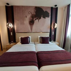 two beds in a room with a painting on the wall at BEYZAA HOTEL AND SUITES in Kolkata