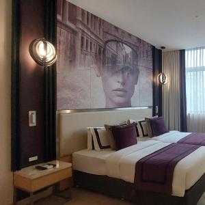 1 dormitorio con 1 cama y una gran pintura en la pared en BEYZAA HOTEL AND SUITES, en Calcuta