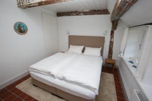 ein Schlafzimmer mit einem großen Bett mit weißer Bettwäsche und einem Fenster in der Unterkunft Pesel in Borgsum