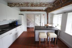 uma cozinha com armários brancos e um balcão com bancos em Pesel em Borgsum