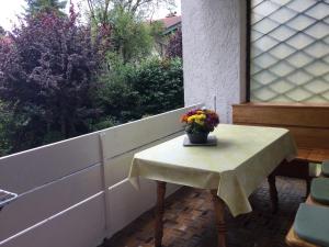 una mesa con un jarrón de flores en el balcón en Alpenwohnanlage Fewo La Rotonda en Grassau