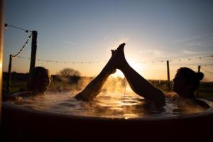 2 femmes dans un bain à remous avec leurs pieds dans l'eau dans l'établissement Huis van Hout - design eco lodge met panorama tuin en hot tub, à Herk-de-Stad