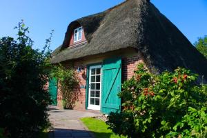 a thatched cottage with a green door at Scheune Borgsum in Borgsum