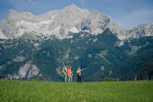 two people standing on a hill with a mountain in the background at Relax- & Wanderhotel Poppengut in Hinterstoder
