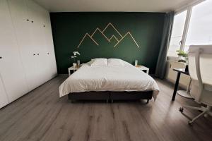 ein Schlafzimmer mit einem Bett und einer grünen Wand in der Unterkunft Airport Access Apartment - Your Gateway to Comfort in Charleroi