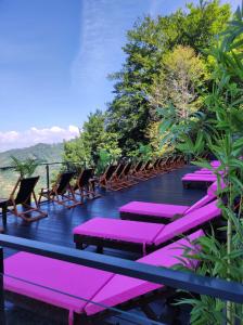una fila de sillas y mesas púrpuras en un balcón en L&N Apartmani Kopaonik-Milmari Resort, en Kopaonik