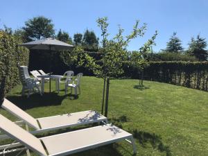 een tuin met een tafel en stoelen en een parasol bij The Suite Escape Apartment Sand in Sint-Lievens-Houtem