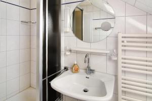 a white bathroom with a sink and a mirror at Strandhus Uiterst-hörn Utkiek in Baltrum +22 photos