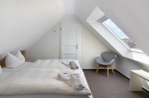 a white bedroom with a bed and a chair at Strandhus Uiterst-hörn Utkiek in Baltrum