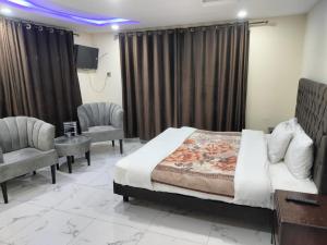 a bedroom with a bed and two chairs and a tv at Unique Heights in Murree +5 photos