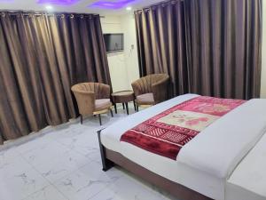 a bedroom with a bed and chairs and curtains at Unique Heights in Murree