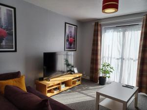 a living room with a couch and a flat screen tv at The Maltings-Old Door - Huku Kwetu Dunstable - 2 Bedroom Apartment-Spacious Business Travelers- 2nd floor Serviced Apartment -Private Parking- Free Wifi in Dunstable