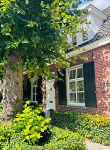 una casa in mattoni con una porta bianca e un albero di Bed and Breakfast: 'Bij ons Achter' a Helvoirt