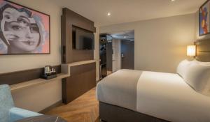 una camera d'albergo con letto e sedia di Maldron Hotel Finsbury Park, London a Londra