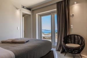 a bedroom with a bed and a chair and a window at Luxusvilla Pylos 6 Personen privater Pool in Gialova