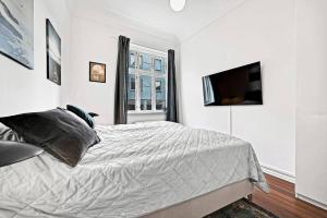 a white bedroom with a bed and a television at The Modern Breakaway in Aarhus in Aarhus