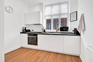 a kitchen with white cabinets and a clock on the wall at The Modern Breakaway in Aarhus in Aarhus