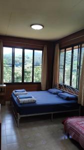 1 dormitorio con 1 cama grande en una habitación con ventanas en บ้านพักพือวา Pue Wa Homestay, en Ban Yang