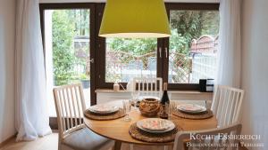 a dining room table with chairs and a yellow lamp at Montana - Ferienwohnung am Laber in Oberammergau