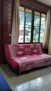 Cama roja en habitación con ventana en บ้านพักพือวา Pue Wa Homestay, en Ban Yang