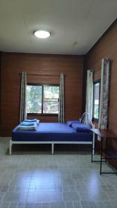a bedroom with a bed with blue sheets and a window at บ้านพักพือวา Pue Wa Homestay in Ban Yang