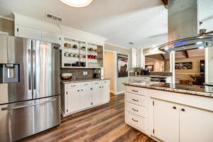 a kitchen with white cabinets and a stainless steel refrigerator at Charming Texarkana Home Lake and Pool Access! in Texarkana