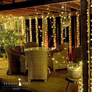 a patio with a table and chairs and lights at Le Chat Vert - Appartements Adults Only in Saint-André