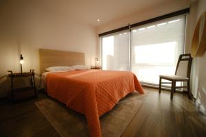 una camera da letto con un letto con una coperta arancione e una finestra di Fonte da Via a Faja Grande
