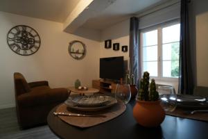 un salon avec une table et une télévision dans l'établissement Le Joli’Mans, appartement refait à neuf, entièrement équipé, pour 2 personnes, proche quartier historique et centre, au Mans