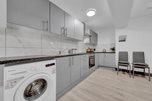 a white kitchen with a washing machine in it at Serviced Ensuite Studio in Feltham London Heathrow in Feltham