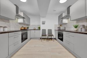a kitchen with white cabinets and two chairs at Serviced Ensuite Studio in Feltham London Heathrow in Feltham
