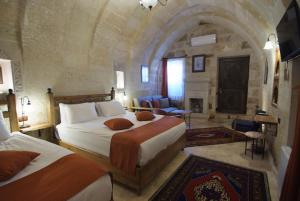una camera da letto con due letti in una stanza in pietra di Peruna Cave a Göreme Altre 81 foto