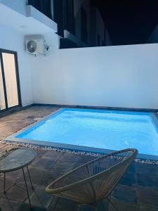 - une piscine avec une chaise et une table dans l'établissement Azure 4 Bedrooms Haven Retreat: Where Tranquility Meets Turquoise Waters, Flic en Flac Mauritius, à Flic-en-Flac