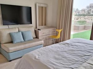 a bedroom with a tv and a couch and a chair at Hawana Salalah Lake View Villa 22 in Salalah