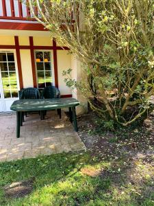 a green bench sitting in front of a building at cottage « maison du golf » à Moliets in Moliets-et-Maa
