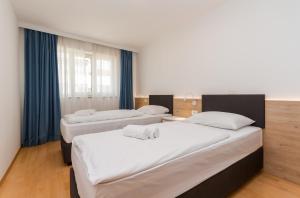 two beds in a room with blue curtains at The Garden Palace Umag by Locap Group in Umag