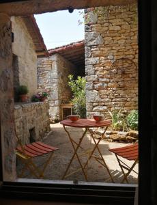 a patio with a table and two chairs and a stone wall at Les Granges de la Leigne, Ruffec in Condac